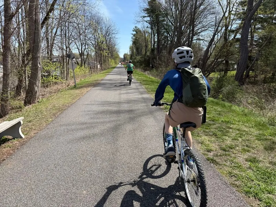 A Scout riding a paved rail trail through spring woods