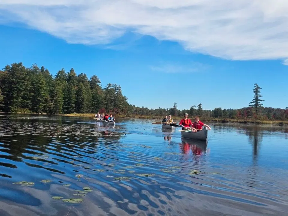 Canoes paddling across calm, blue Lows Lake under a wide sky