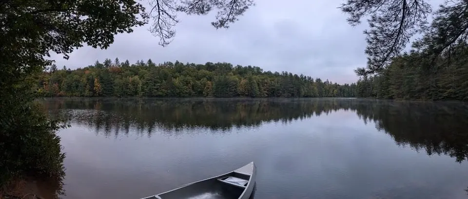 Panorama of a still Adirondack lake from the bow of a canoe