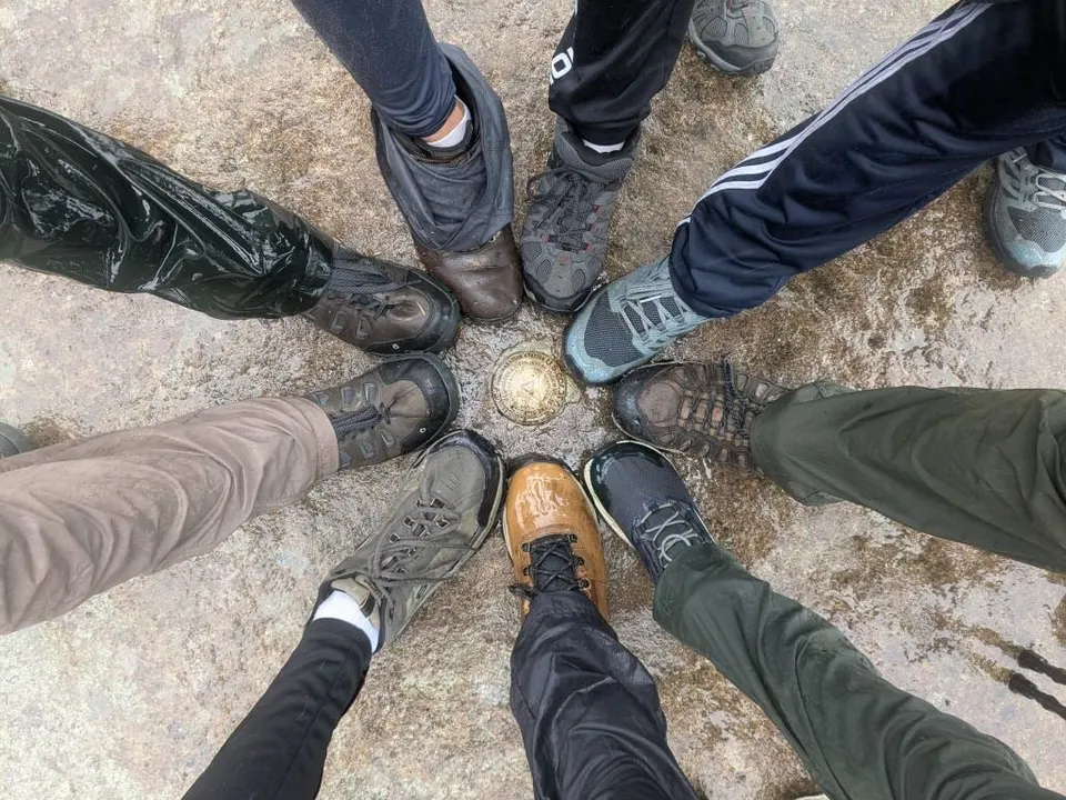 Hikers' boots in a circle around the survey marker on a summit