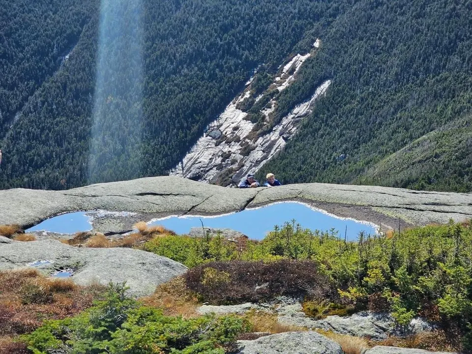 Looking down from a summit at a small alpine pond and a rock slide on the mountainside