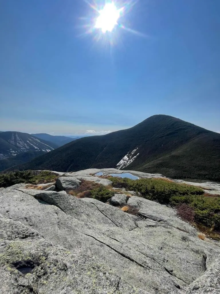 The sun blazing over a bare rock summit in the High Peaks