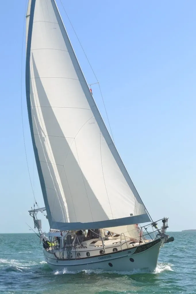 A sailboat heeling in the wind under a bright sky