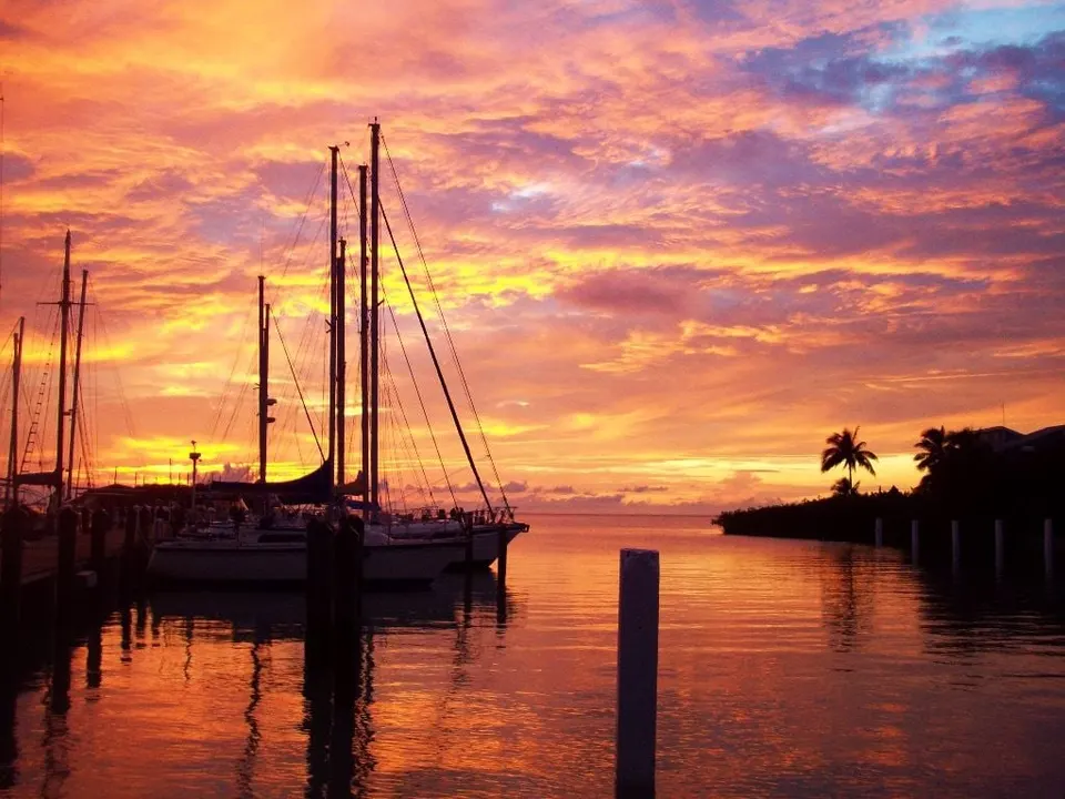 Sailboat masts silhouetted against a blazing sunset