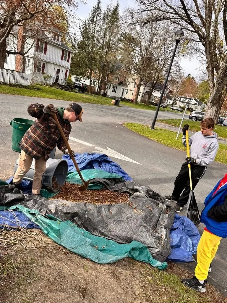 Scouts raking leaves onto tarps at a spring church clean-up