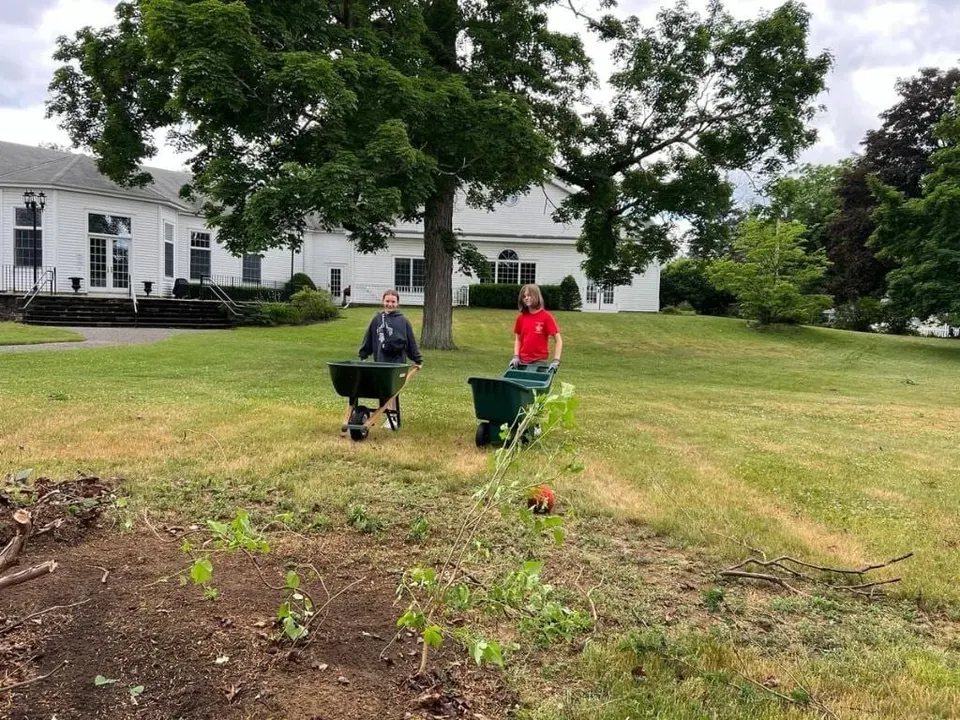 Scouts with wheelbarrows working on a garden bed outside the church