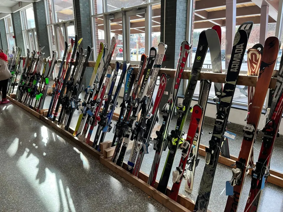 A long rack of downhill skis along the cafeteria windows