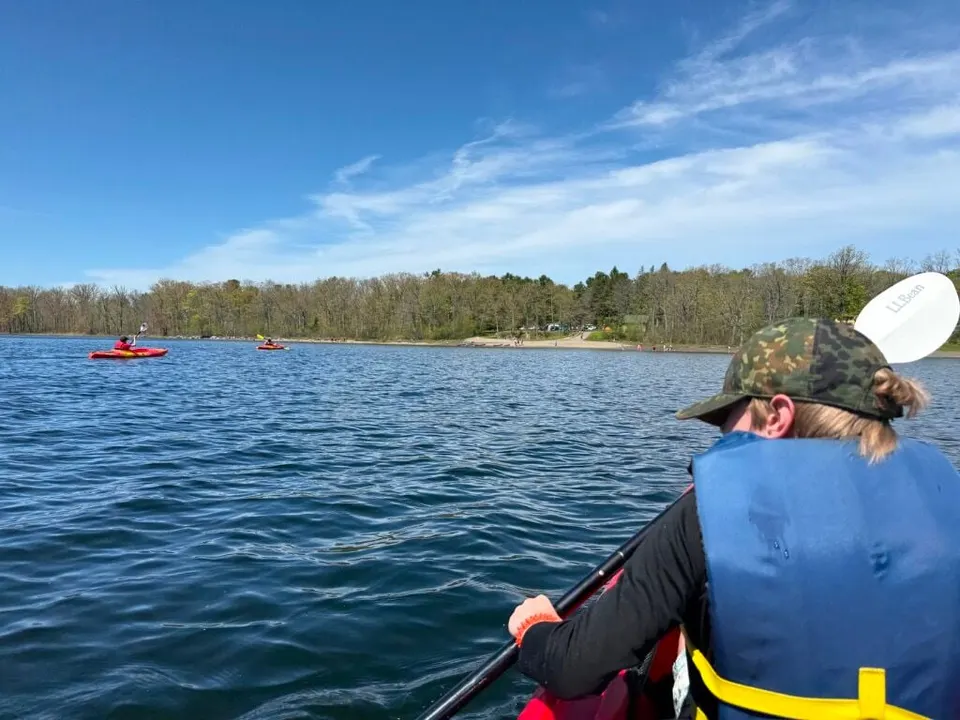 A Scout in a life jacket paddling a kayak out onto Thompson's Lake