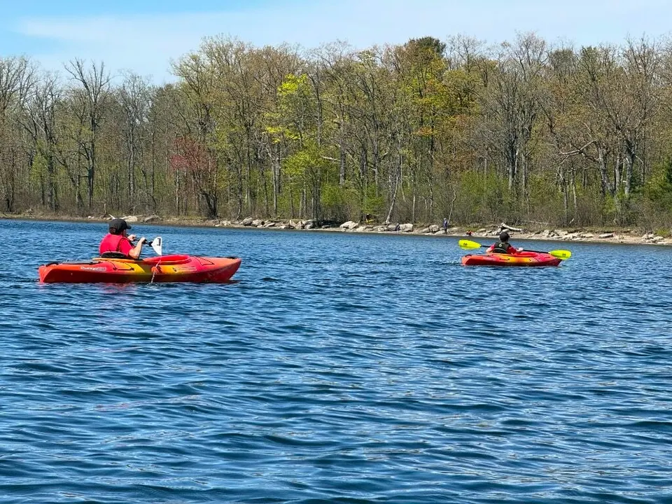 Kayakers in red boats spread out across the lake