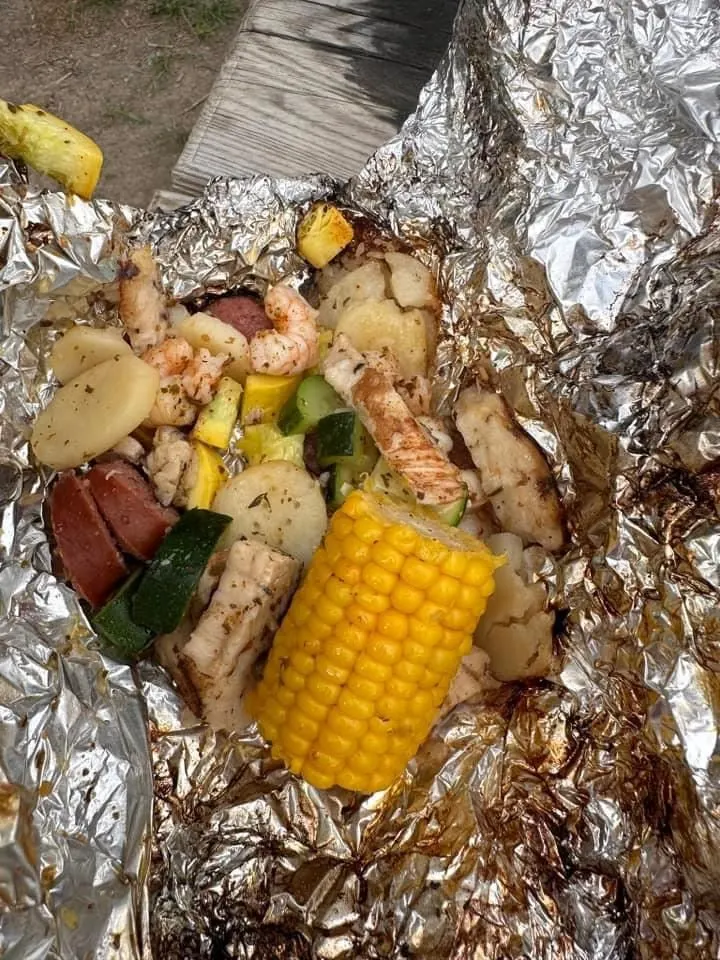 A foil-packet dinner with corn on the cob, fresh off the coals