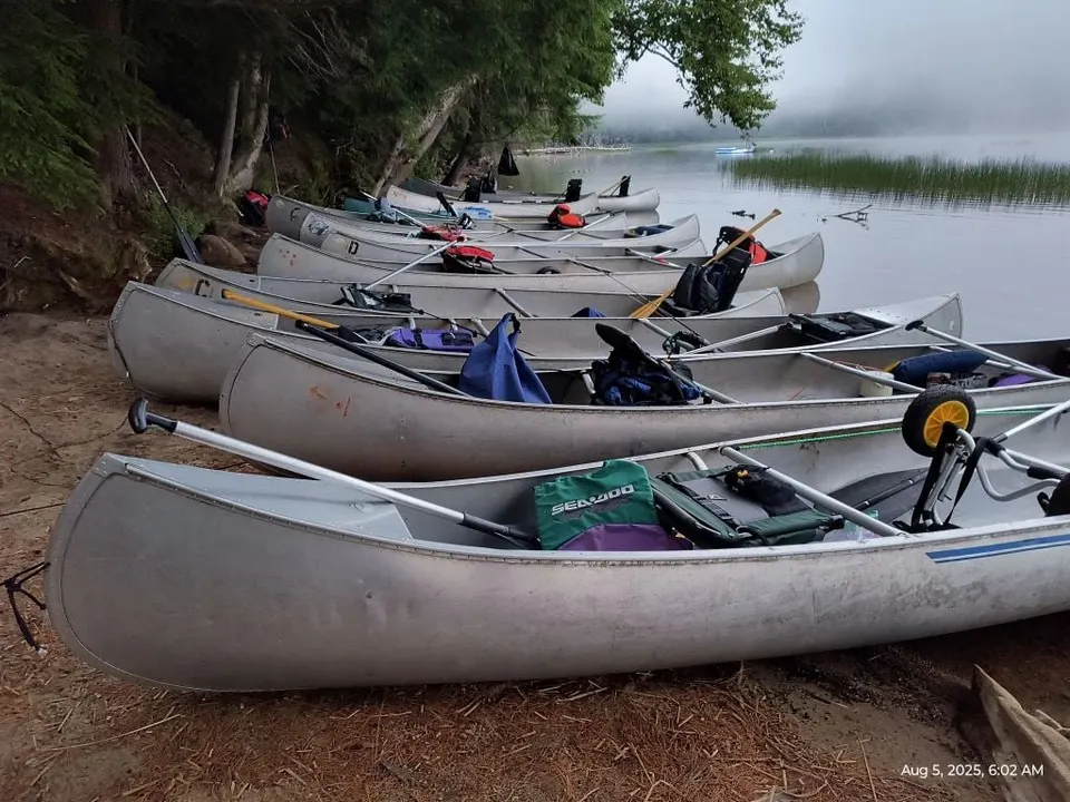 A row of loaded canoes on the beach at dawn, ready to launch