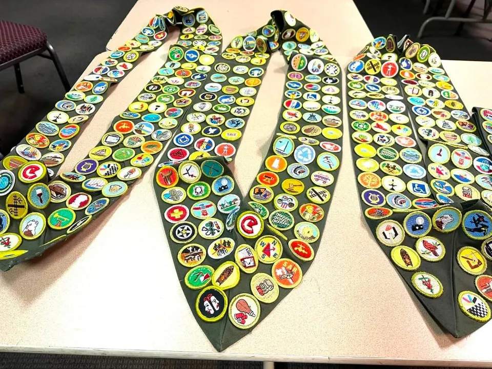 Merit badge sashes laid side by side, each covered in badges